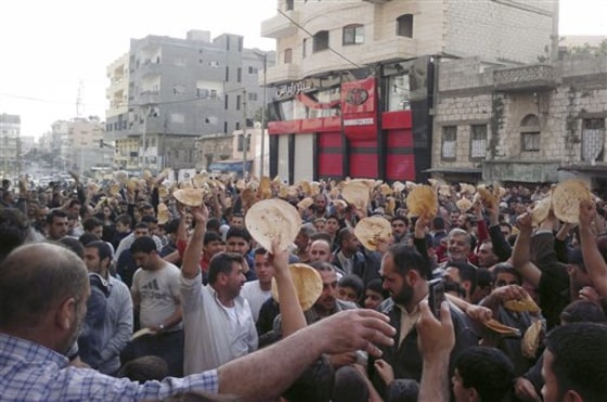 In this citizen journalism image from May 3, Syrian men carry bread loaves during a protest against Syrian President Bashar Assad's regime, in the coastal town of Banias. Facing international condemnation for its bloody crackdown on protesters, the Syrian regime is expanding an intimidation campaign to keep people off the streets, according to human rights activists. 